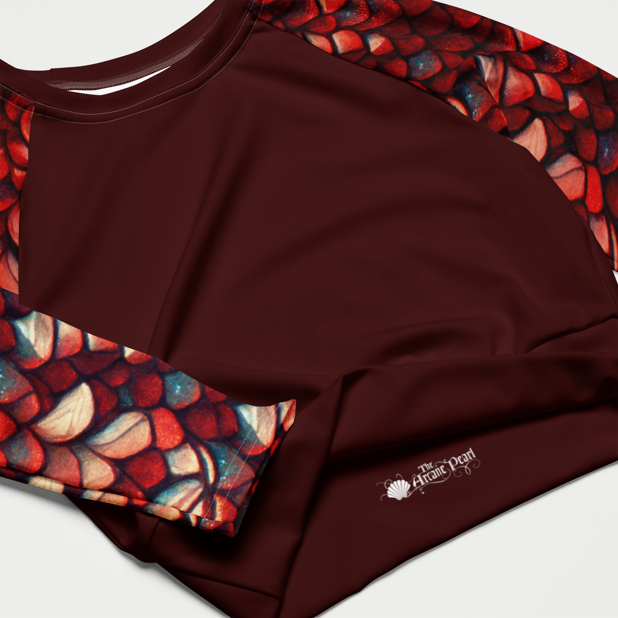 A close-up of a long-sleeve athletic top in deep burgundy with abstract multicolor shell-like patterns along the shoulders and sleeves. 