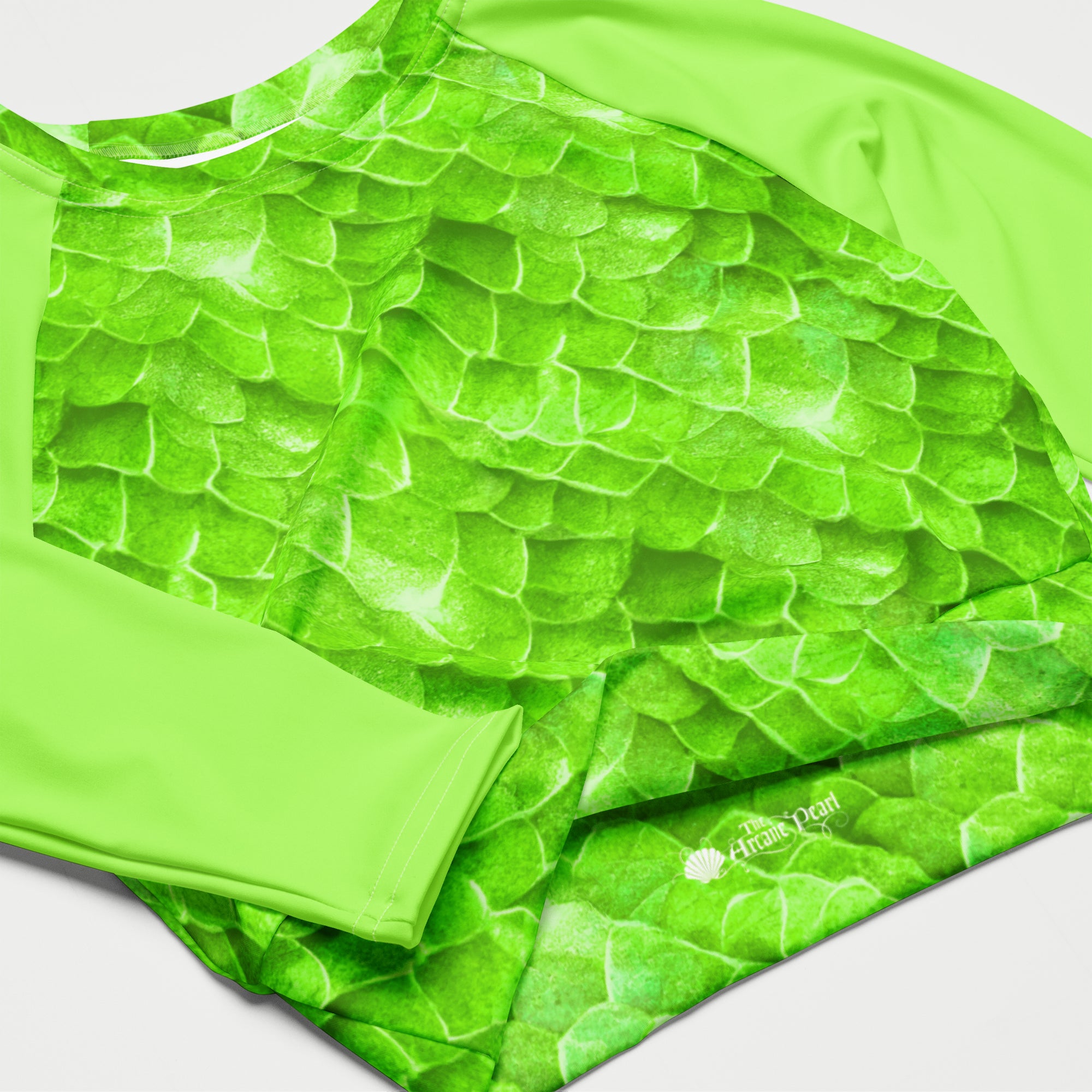 A close-up of a bright green athletic top with a textured, scale-like pattern and a matching green sleeve, laid flat on a light gray background. 