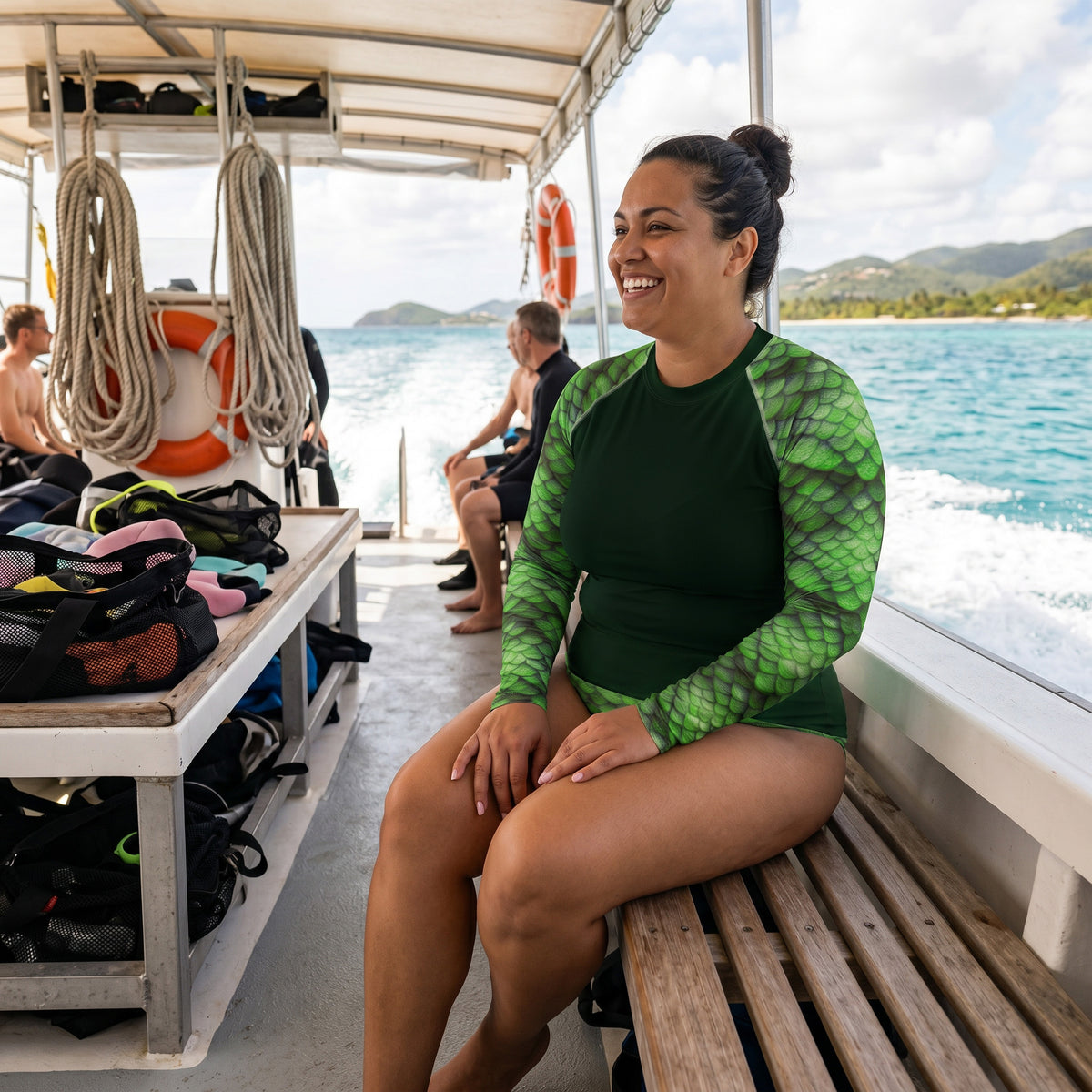 Woman in a green rash guard sitting on a boat with water and mountains in the background